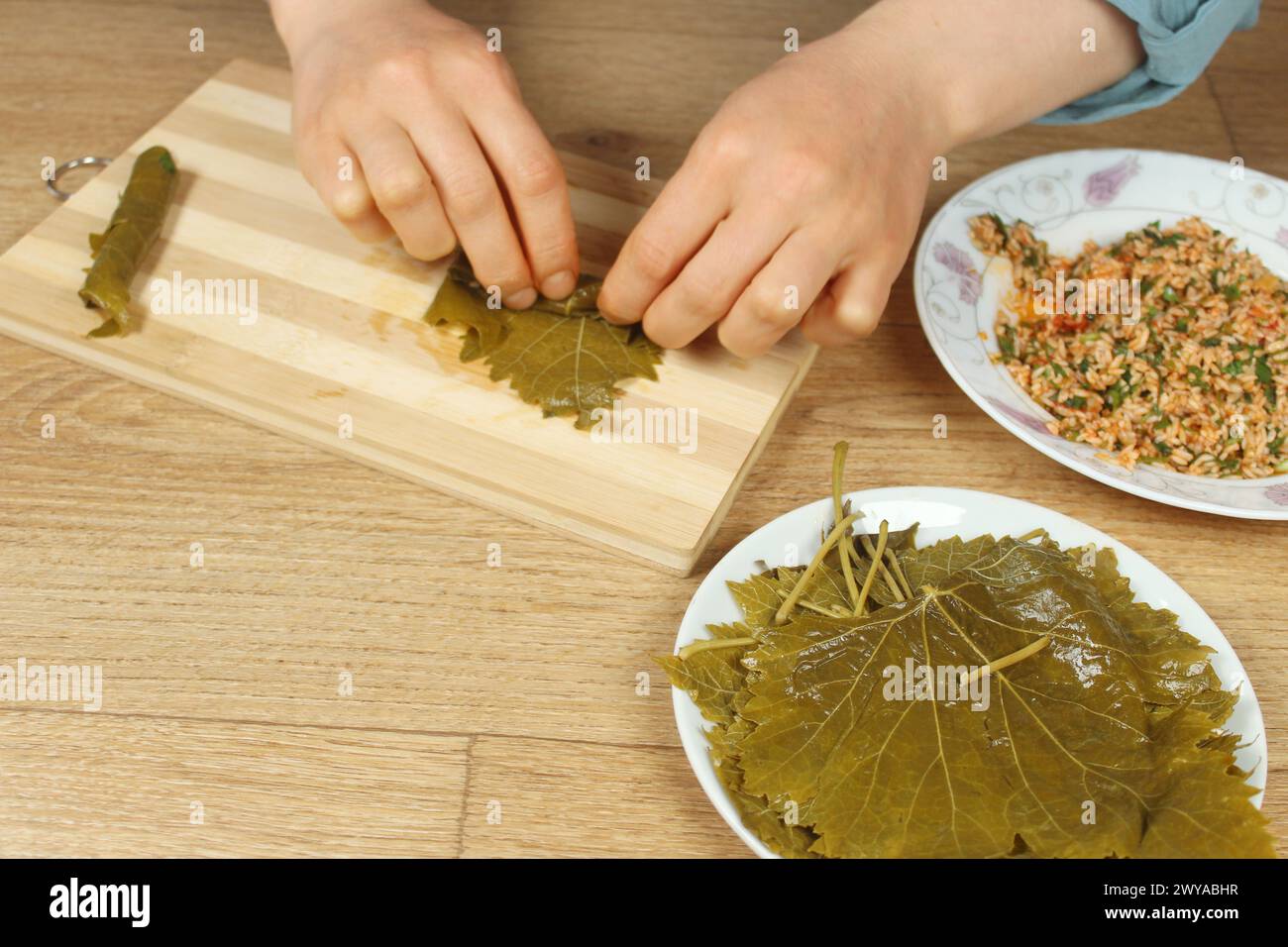 Mains de femme préparant l'emballage farci avec l'ingrédient de riz. Cuisine grecque ou turque Yaprak Sarma ou Dolma préparation. Nourriture traditionnelle égéenne en Turquie. Banque D'Images