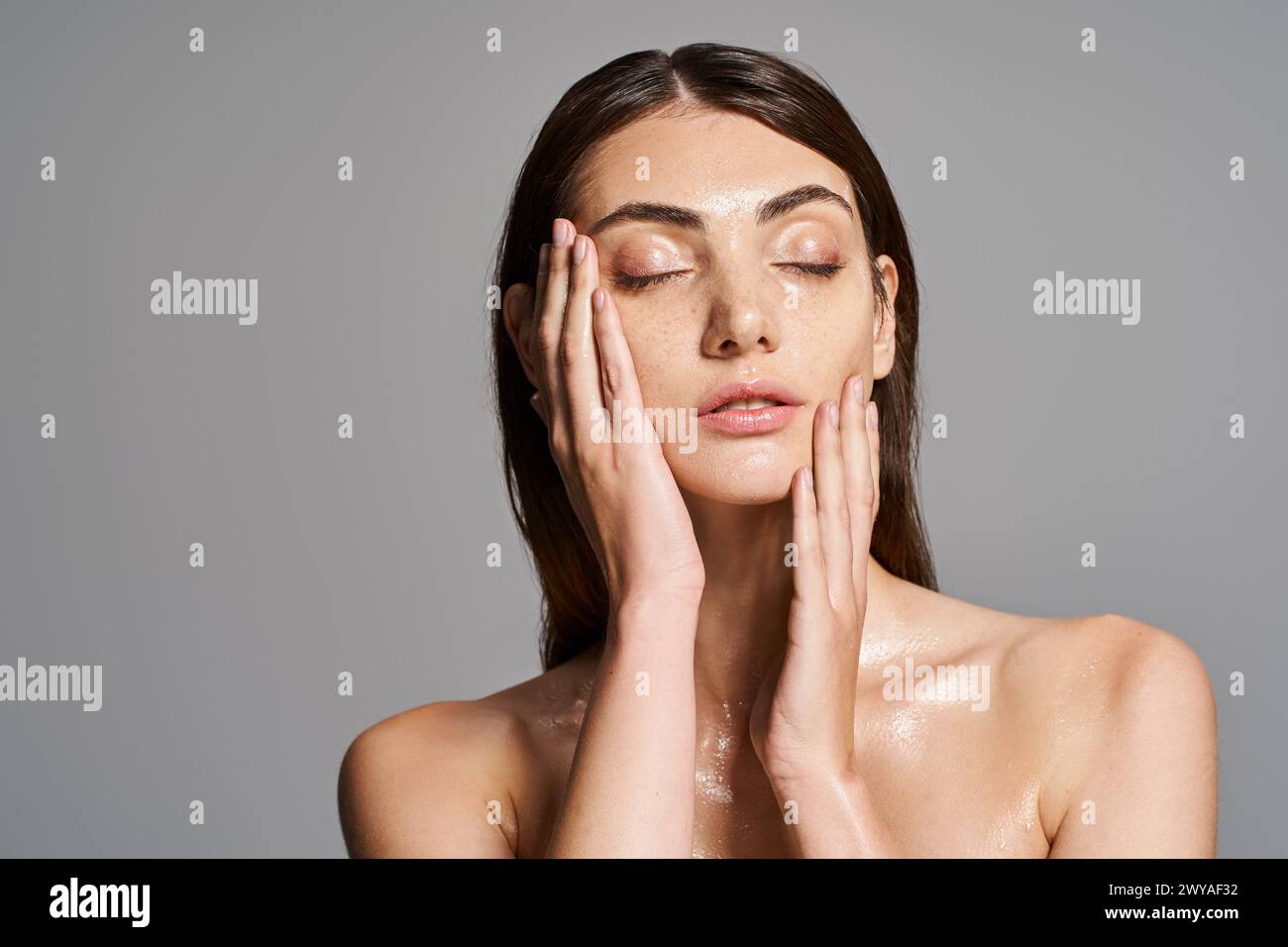 Une jeune femme caucasienne aux cheveux bruns tenant les mains sur son visage dans un moment de réflexion profonde et d’introspection. Banque D'Images
