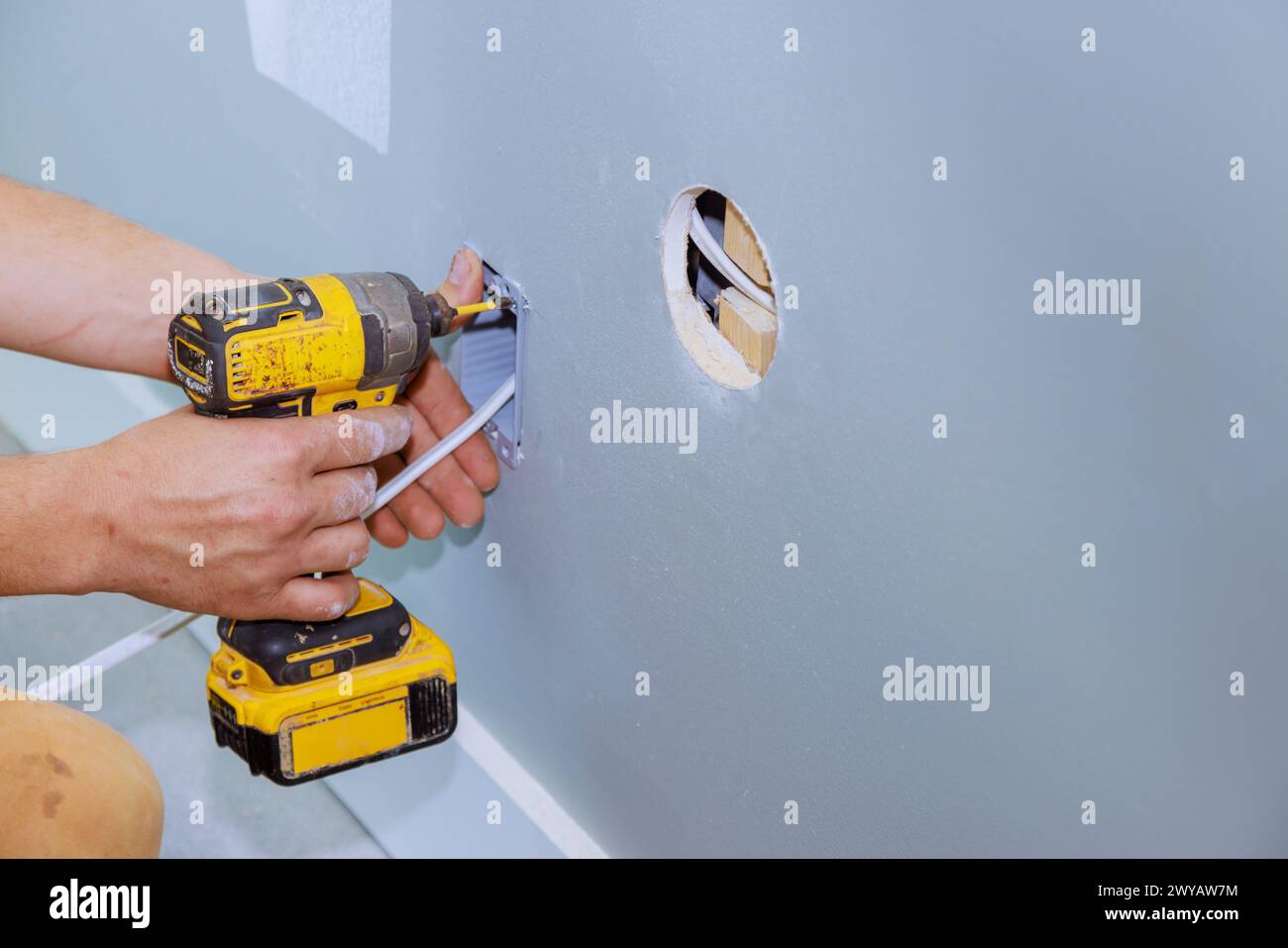 Électricien professionnel installant une prise électrique dans le mur du système électrique de la pièce de rénovation Banque D'Images