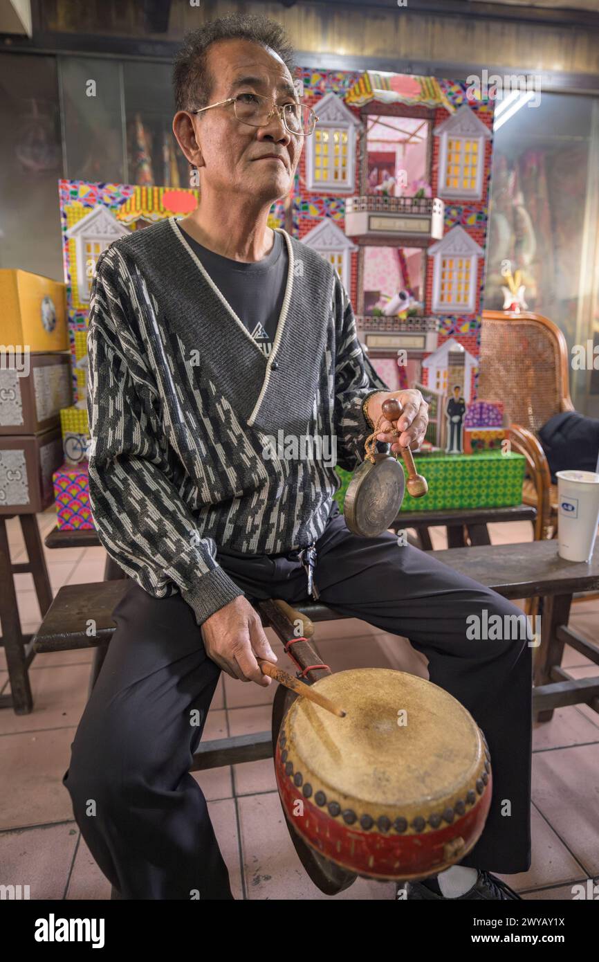 Un homme est assis à jouer un tambour traditionnel à l'intérieur d'une salle de temple remplie d'objets rituels lors d'une cérémonie dans le temple Dongyue Hall Banque D'Images