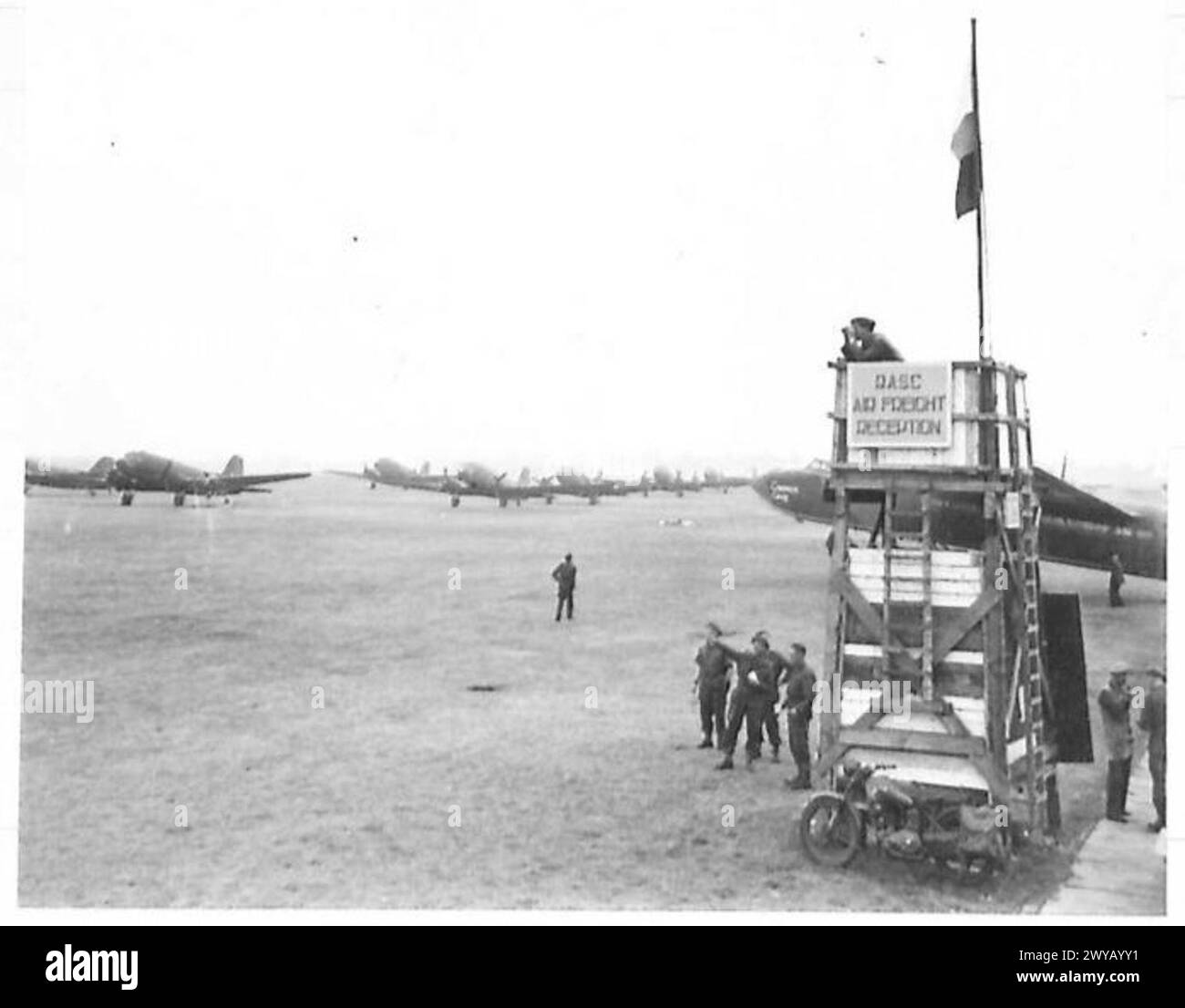 Opérations de fret aérien de la R.A.S.C. avec des véhicules de transport attendant autour de la tour de contrôle, officier de contrôle visible, Armée britannique, 21e Groupe d'armées. Banque D'Images