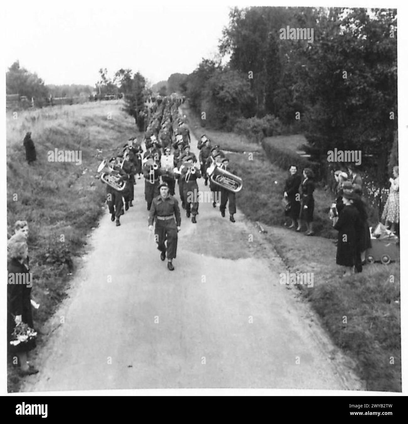 Des parachutistes canadiens dirigent une bande et marchent vers un cimetière pour un service commémoratif en temps de guerre. Banque D'Images