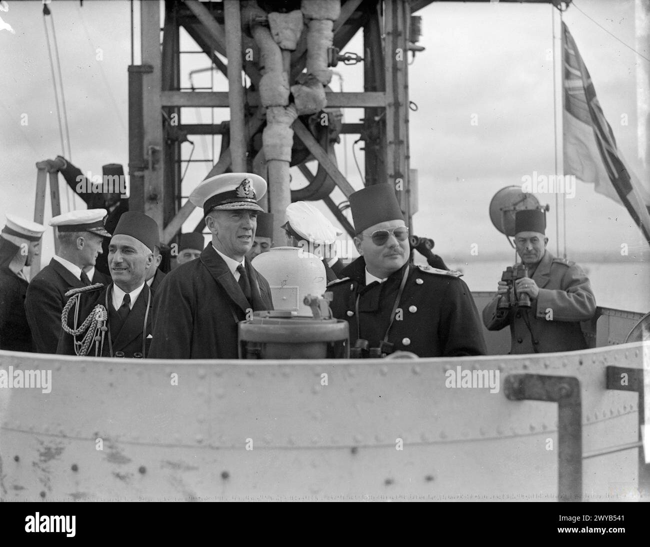 LE ROI FAROUK VISITE LE PORTE-AVIONS D'ESCORTE BRITANNIQUE. MARS 1945, À BORD DU HMS HUNTER, ALEXANDRIE, ÉGYPTE. - Le roi Farouk avec le vice-amiral W G Tennant, CBE, MVO, l'officier du drapeau Levant et la Méditerranée orientale, sur le pont du HMS HUNTER. Sur la gauche se trouve le vice-amiral Mahmoud Hamza Pacha. , Banque D'Images