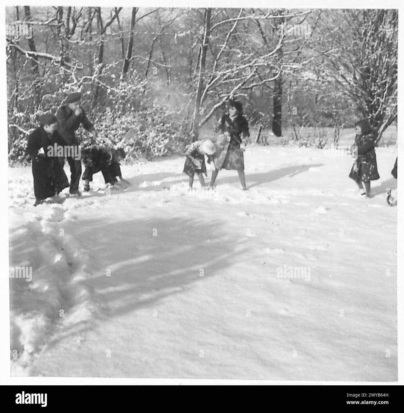 Un soldat britannique s'engage dans un combat de neige avec des enfants, servant de moral et de bonne volonté. Banque D'Images