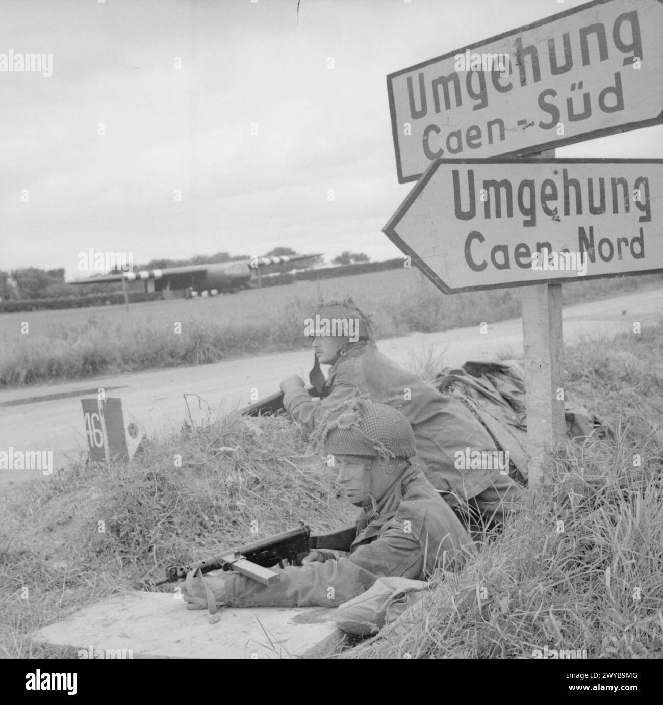 Les caporaux A. Burton et L. Barnett du corps de police militaire, 6e division aéroportée, gardent un carrefour près de Ranville le 9 juin 1944, avec des planeurs Horsa visibles derrière pendant la campagne de Normandie. Banque D'Images