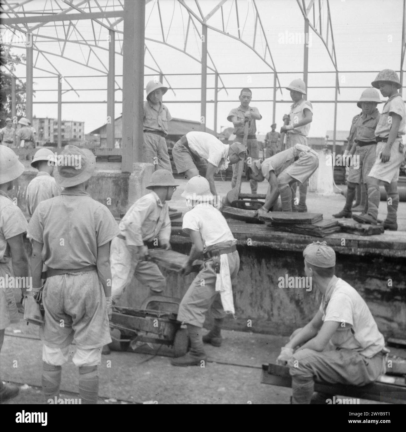 En 1945, les prisonniers de guerre japonais à Singapour se voient confier des tâches, notamment le déplacement de blocs de béton sur les quais pour soutenir la reconstruction de la ville d'après-guerre. Banque D'Images