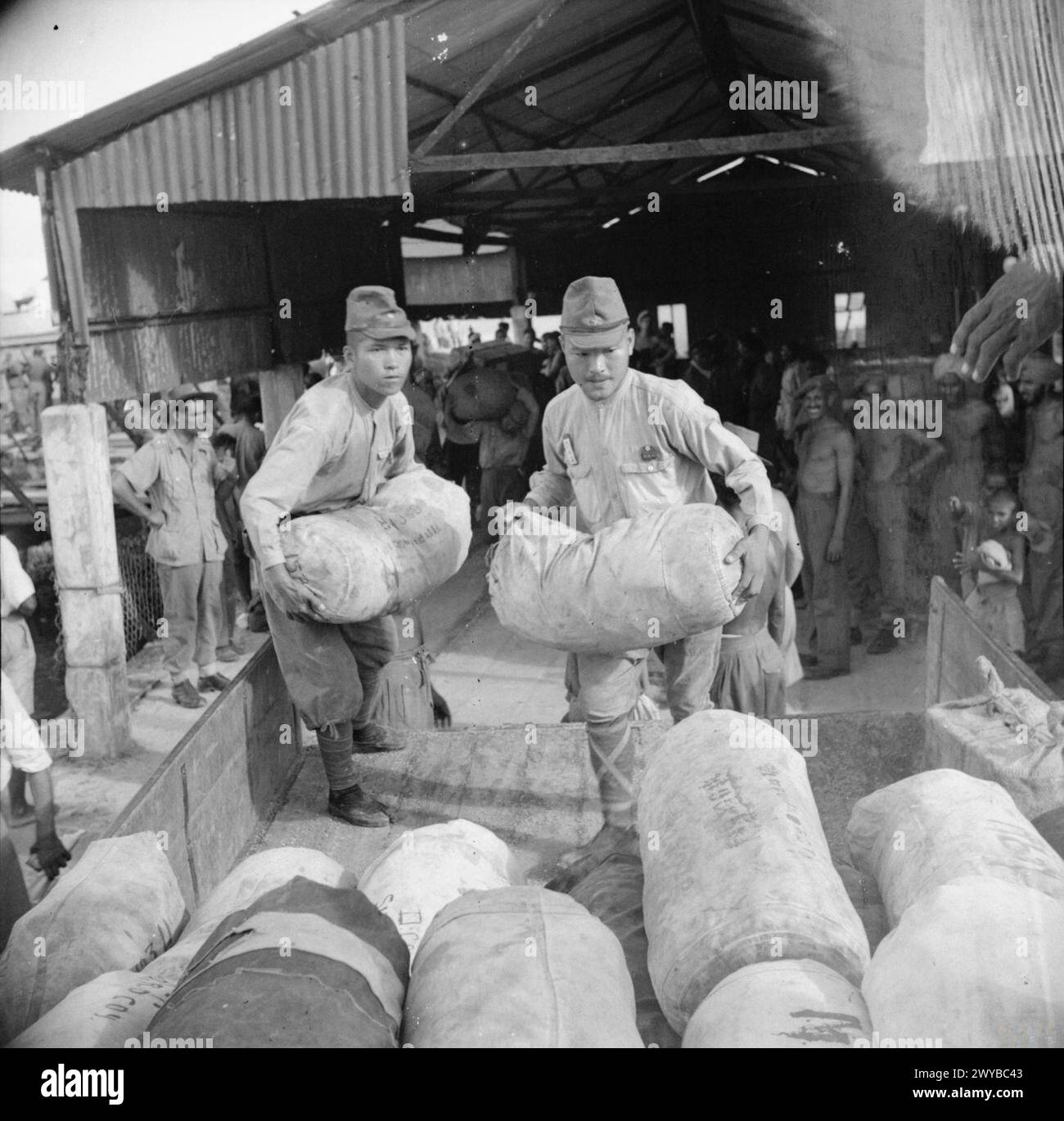 LA RÉOCCUPATION ALLIÉE DES ÎLES ANDAMAN, 1945 - les soldats japonais déchargent des entrepôts pour les forces d'occupation alliées à Port Blair dans les îles Andaman. , Banque D'Images