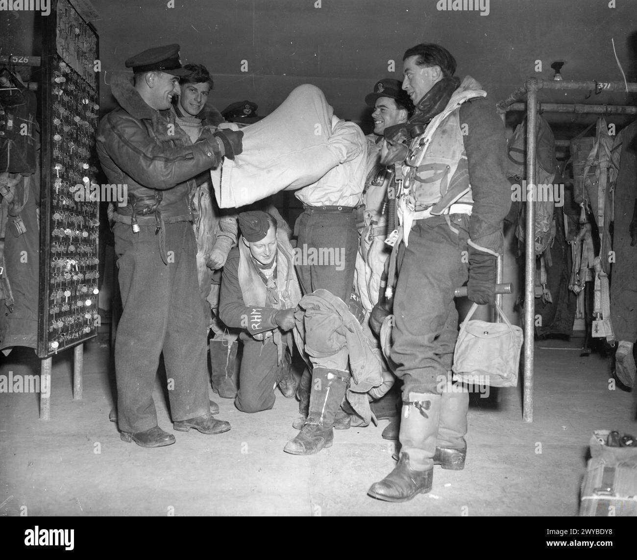 Le 1-2 mars 1944, l'équipage de la RAF revient d'une attaque contre Stuttgart. Les membres de l'équipage ont aidé un autre membre à enlever des vêtements supplémentaires après la sortie. Banque D'Images