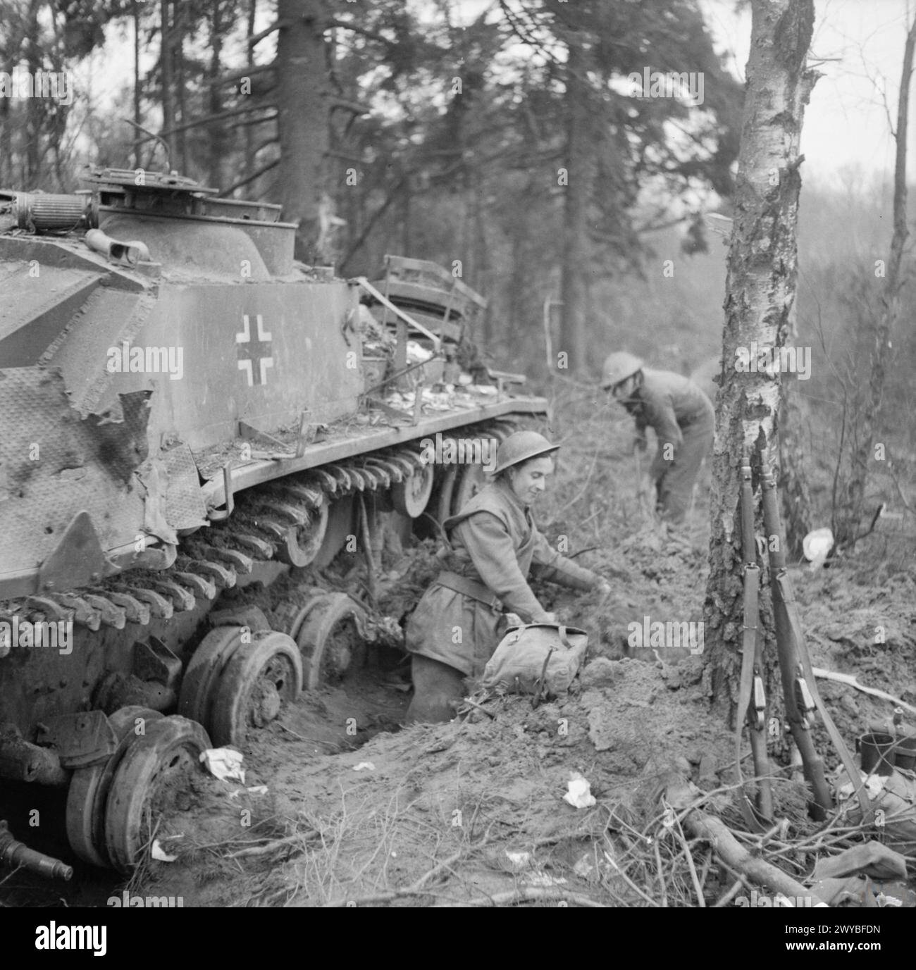 Les hommes du 4e Royal Welch Regiment construisent une excavation à côté d'un canon d'assaut allemand StuG III détruit près de Weeze, en Allemagne, le 3 mars 1945 lors des opérations de l'armée britannique dans le nord-ouest de l'Europe. Banque D'Images