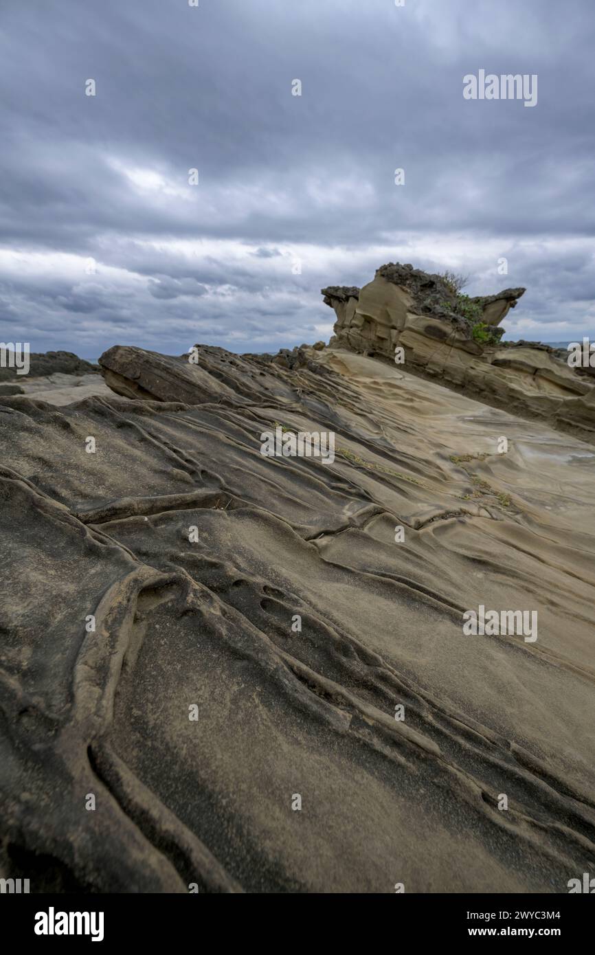 Une journée couverte sur une rive rocheuse présentant des modèles uniques de trous d'érosion avec des vagues rugueuses en arrière-plan Banque D'Images