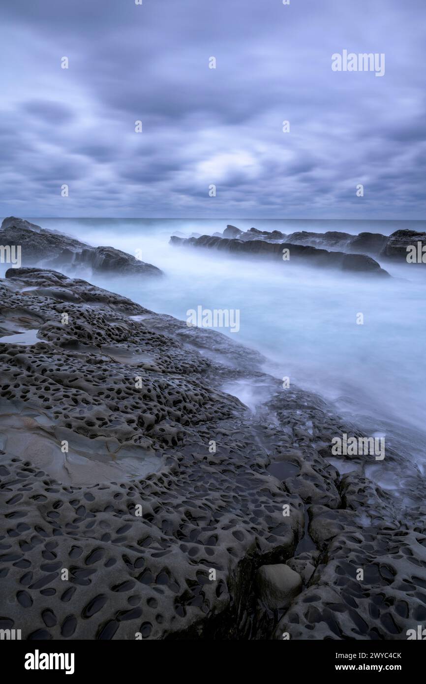 Atmosphère mystique avec des rochers lisses et altérés sur une côte rugueuse, sous un ciel couvert Banque D'Images