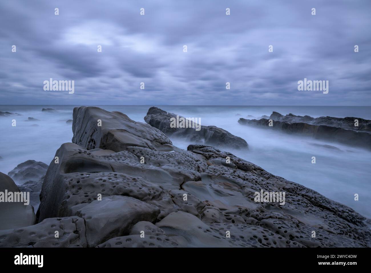 Atmosphère mystique avec des rochers lisses et altérés sur une côte rugueuse, sous un ciel couvert Banque D'Images