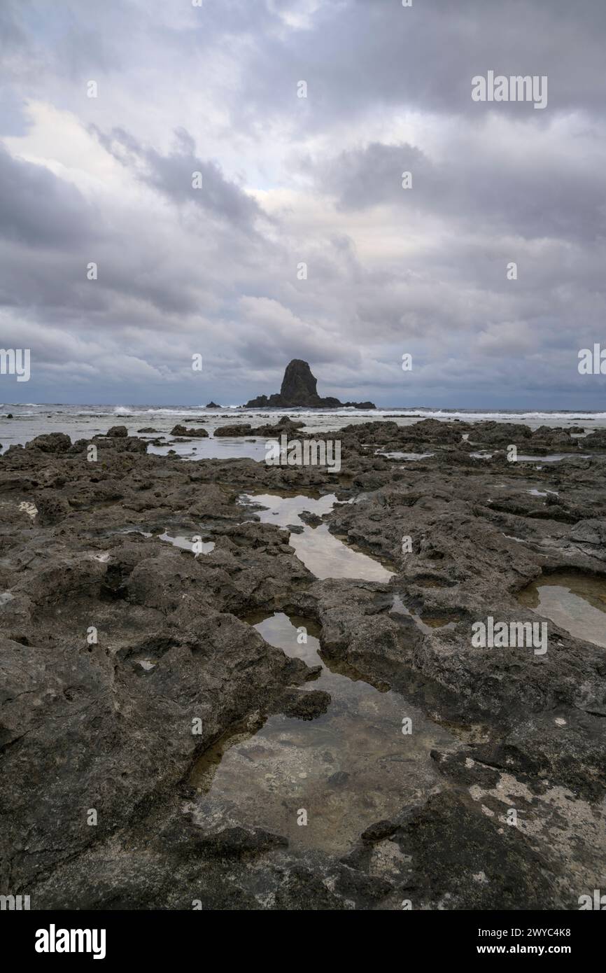 Une douce cascade coule des roches moussues dans les marées avec pour toile de fond des formations rocheuses côtières pointues Banque D'Images