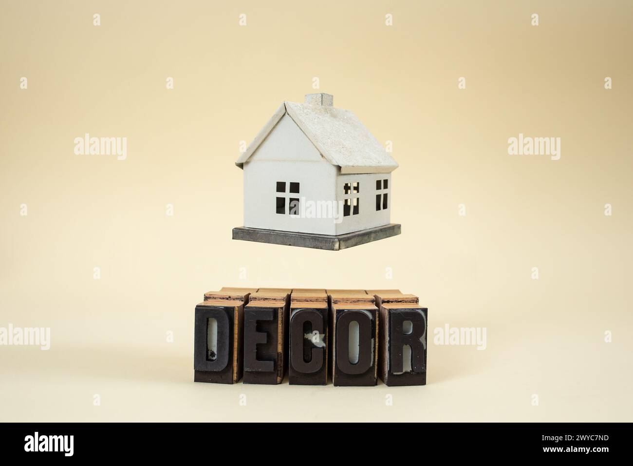 Modèle de maison en lévitation miniature sur le mot de décor écrit avec des lettres de timbre sur beige Banque D'Images