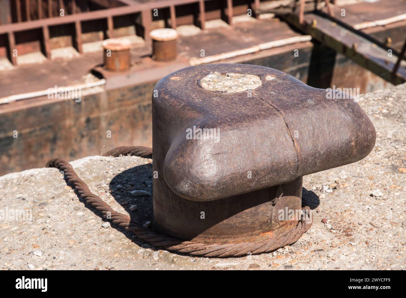 Vieux poteau d'amarrage de quai en métal avec corde d'acier pour sécuriser le navire de barge de vrac de rivière en gros plan Banque D'Images