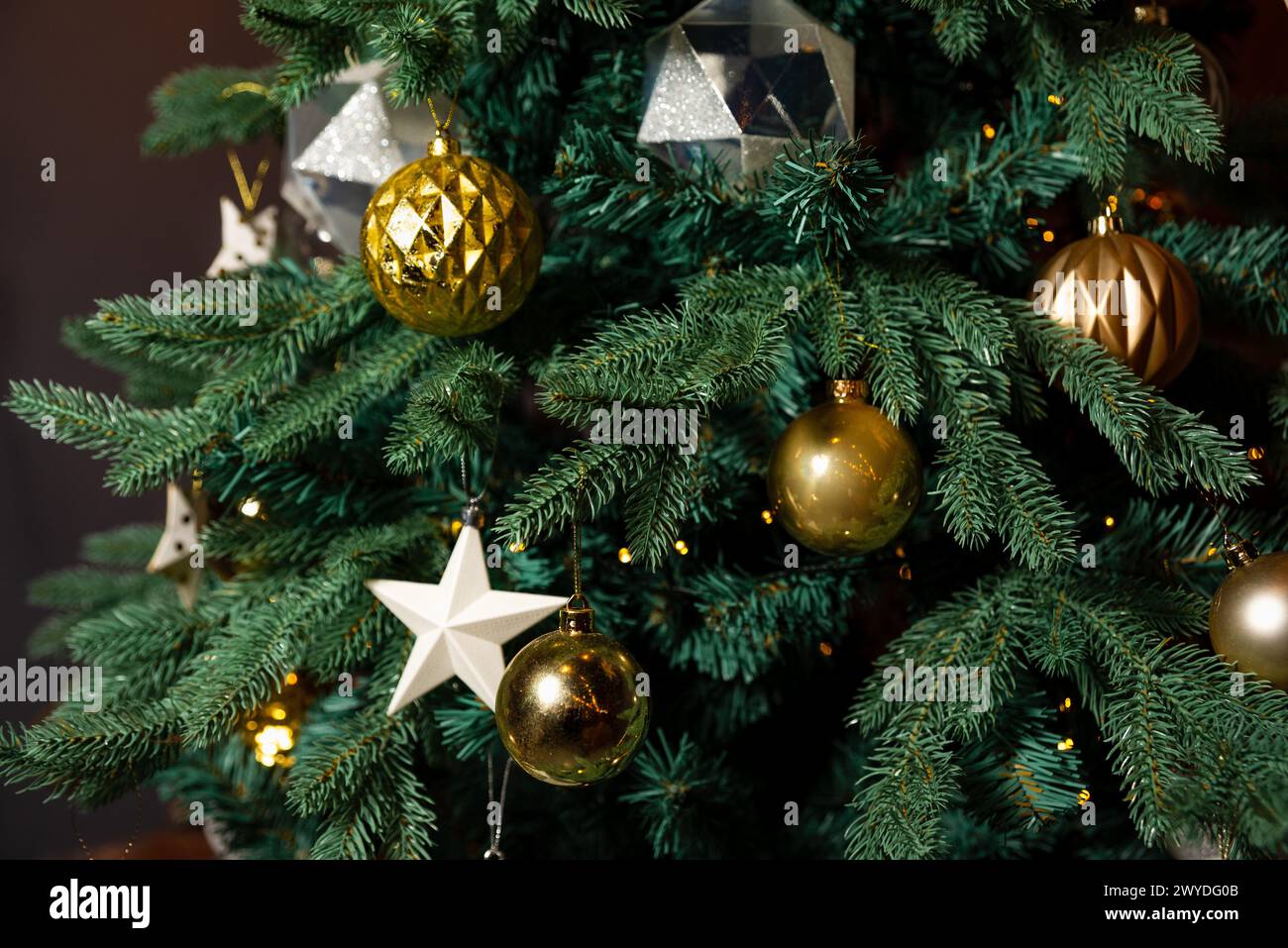 Un sapin de Noël magnifiquement décoré avec un mélange d'ornements or et argent, ajoutant une touche d'élégance à la décoration festive. Banque D'Images