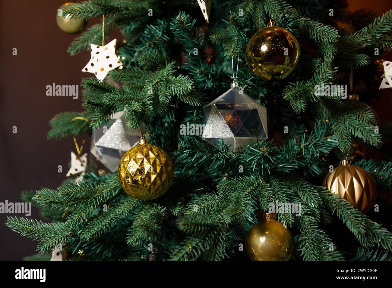 Un sapin de Noël magnifiquement décoré avec un mélange d'ornements or et argent, ajoutant une touche d'élégance à la décoration festive. Banque D'Images