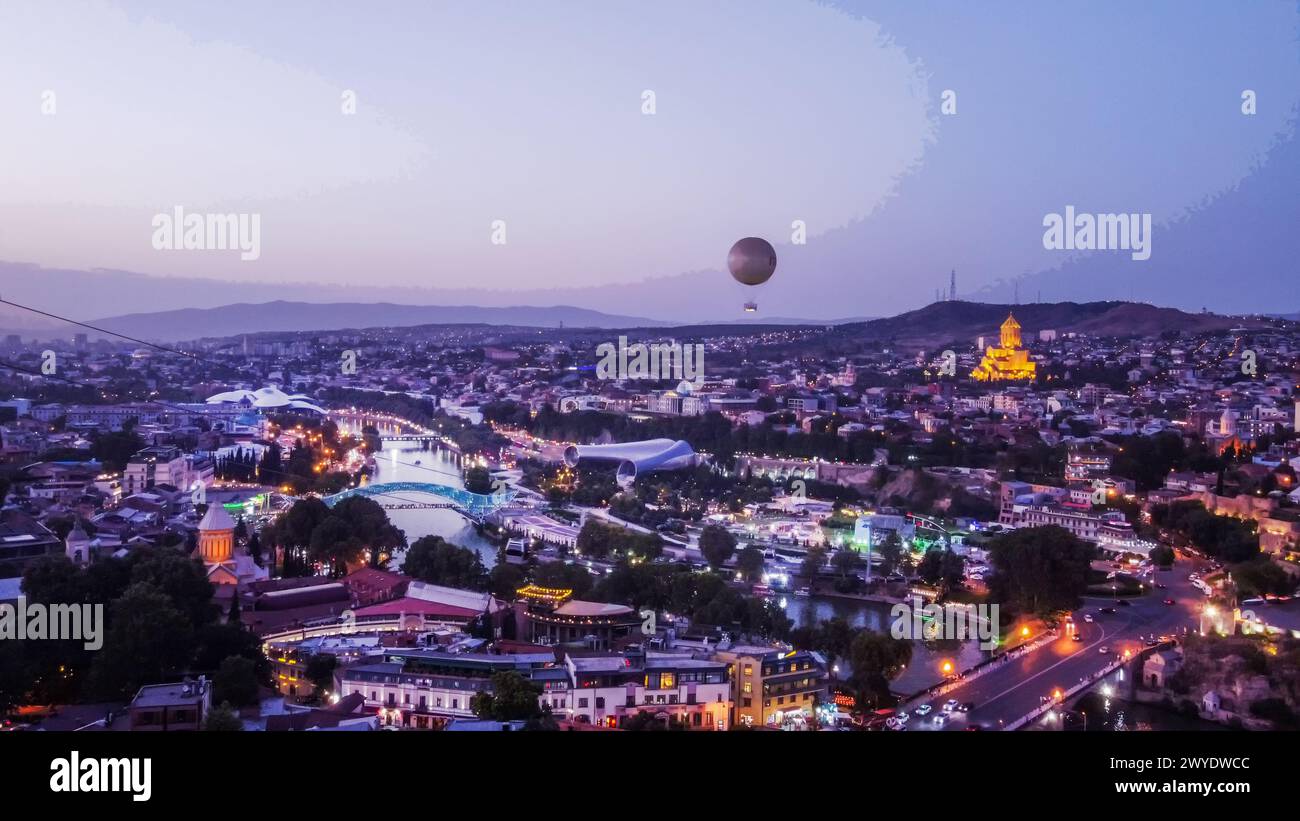 Fantastique vue d'heure bleue sur Tbilissi -capitale géorgienne avec pont de la paix, rivière Kura et églises chrétiennes orthodoxes illuminées Banque D'Images