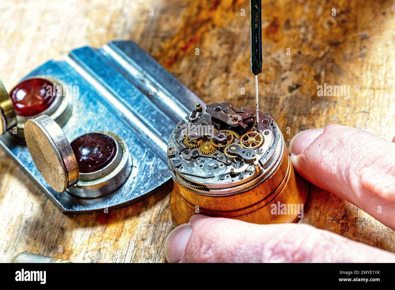 L’art précis de l’horlogerie se déploie alors qu’un horloger met des roues en mouvement sur un banc en bois Banque D'Images