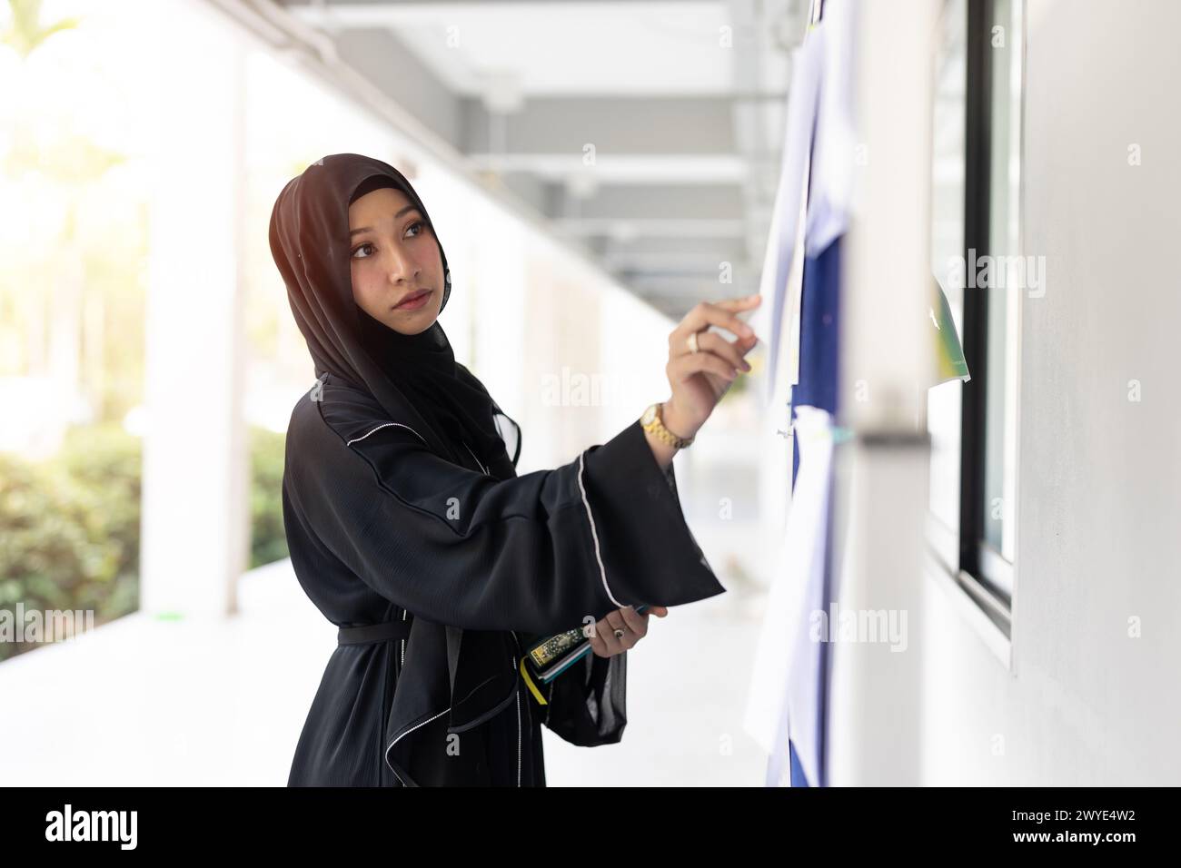 University muslim teen girl à la recherche d'un emploi à temps partiel poste de travail au panneau publicitaire des emplois du campus. Les Arabes regardent le panneau d'affichage. Banque D'Images