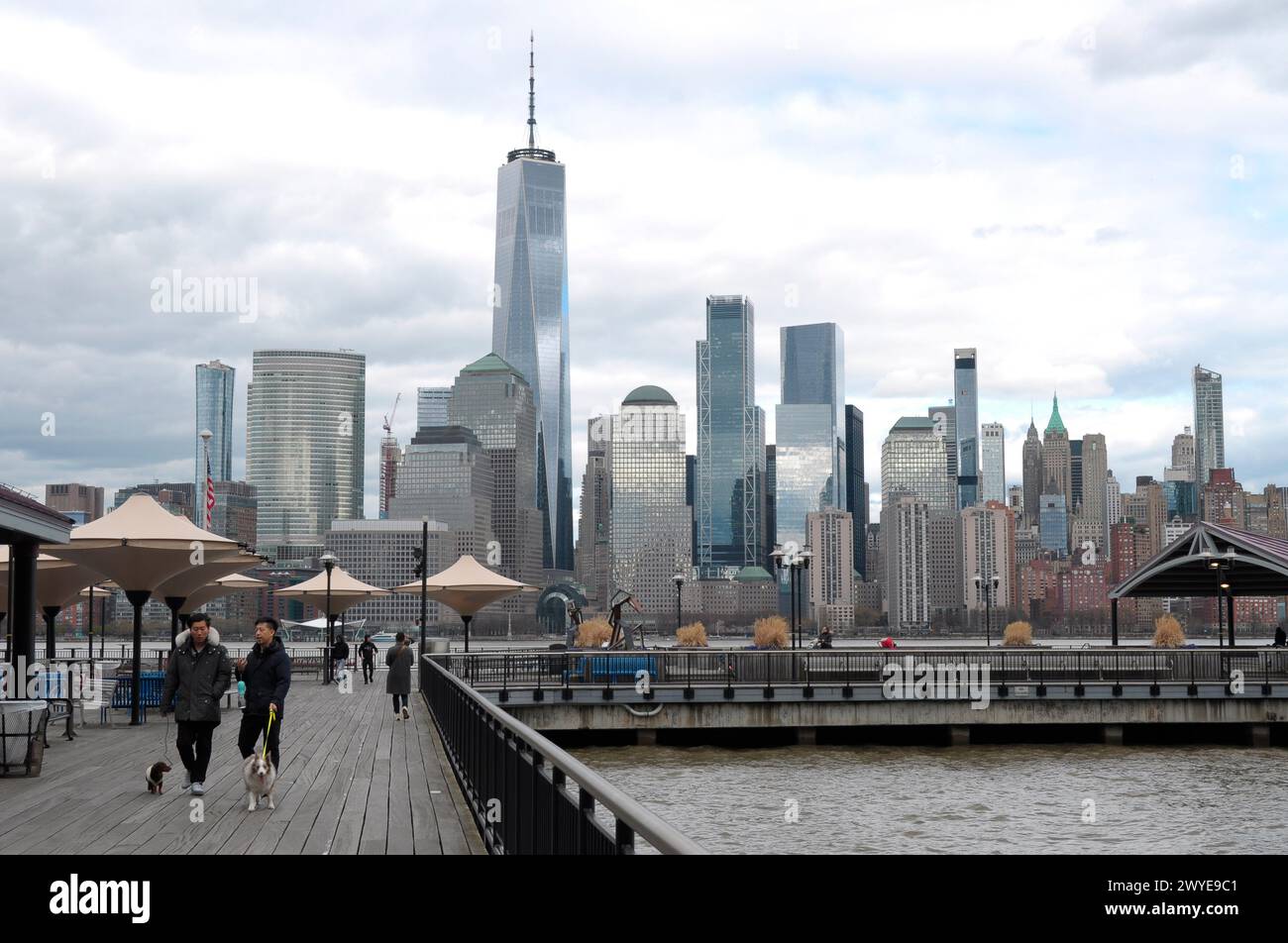 Les gens promènent des chiens dans un parc au bord de la rivière Hudson à Jersey City, New Jersey comme l'horizon de New York City et le One World Trade Center sont vus en arrière-plan. Dans la matinée du 5 avril, New York et le New Jersey ont été frappés par des tremblements d'un tremblement de terre de magnitude 4,8 en provenance du New Jersey selon le United States Geological Survey. L'agence gouvernementale a déclaré que les tremblements du tremblement de terre ont également été ressentis à Philadelphie et Boston. Aucun dommage important n'a été signalé à New York ou dans le New Jersey. Banque D'Images