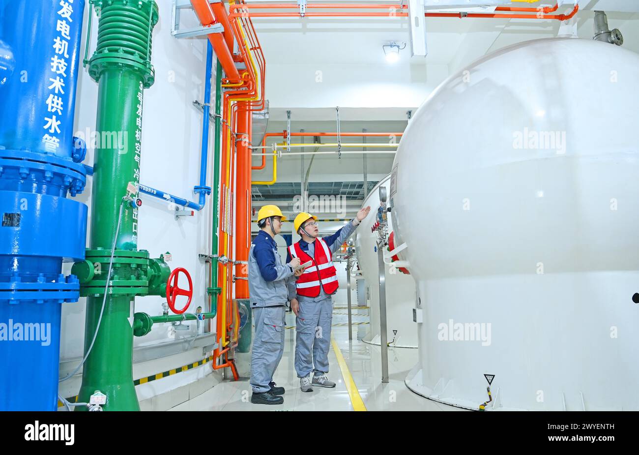 WUHU, CHINE - 6 AVRIL 2024 - des ouvriers révisent et entretiennent un groupe électrogène dans un bâtiment souterrain du groupe Xiangshuijian du réseau d'État Xinyuan Banque D'Images