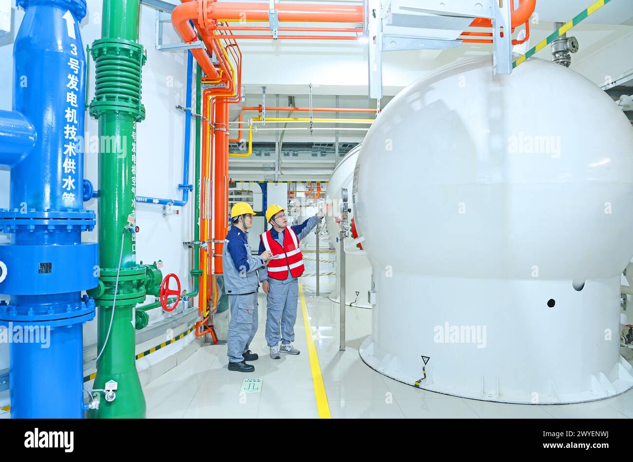 WUHU, CHINE - 6 AVRIL 2024 - des ouvriers révisent et entretiennent un groupe électrogène dans un bâtiment souterrain du groupe Xiangshuijian du réseau d'État Xinyuan Banque D'Images