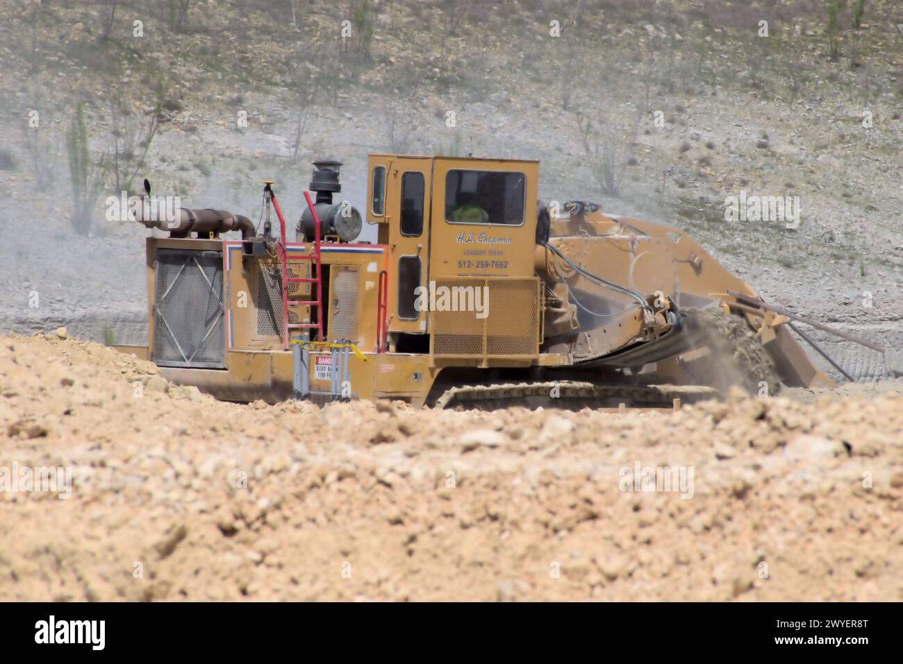 Équipement d'excavation nivelant les collines du Texas Hill Country pour soutenir l'étalement urbain, que beaucoup voient comme une transformation négative à la vie rurale/ranch. Banque D'Images