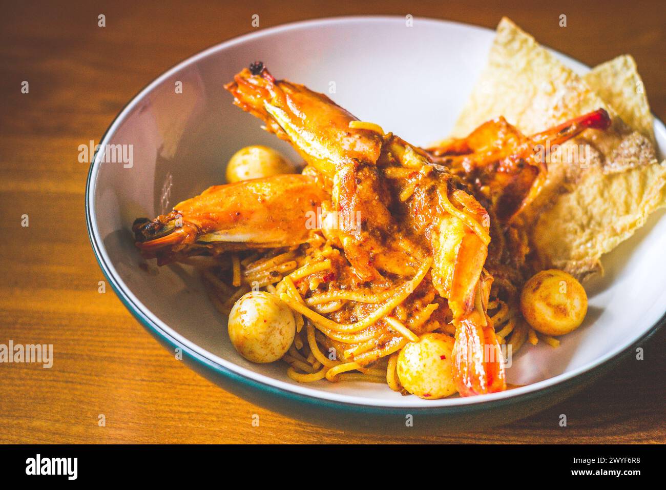 Pâtes Laksa aux crevettes King Tiger, œuf de caille, lait de coco épicé et spaghetti servis dans un bol Banque D'Images