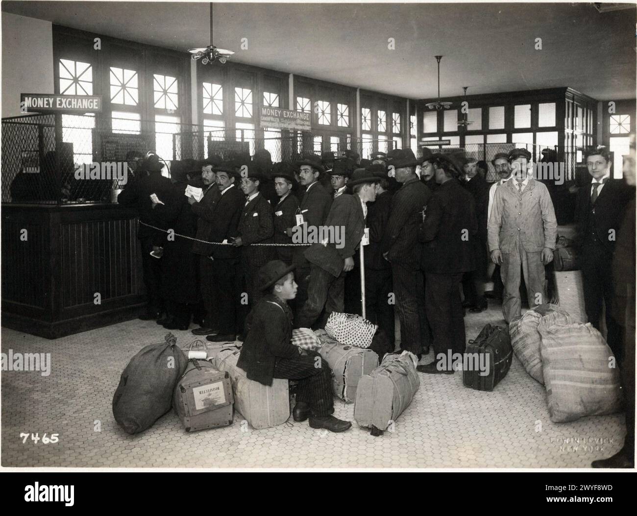 Les immigrants avec des bagages alignés aux guichets du guichet du guichet marquaient l'échange d'argent. Banque D'Images