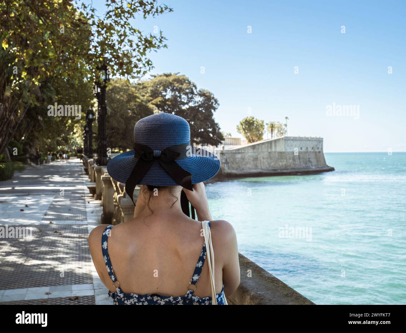 Une jeune fille dans une robe bleue et chapeau prenant une photo des murs de la ville avec le bastion Baluarte de la Candelaria et le parc d'Alameda Apodaca en th Banque D'Images