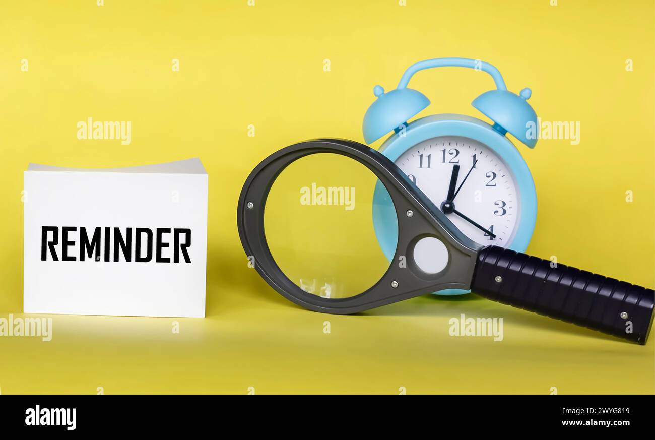 Il y a une horloge et une loupe sur fond jaune, avec l'inscription RAPPEL sur l'autocollant. Banque D'Images
