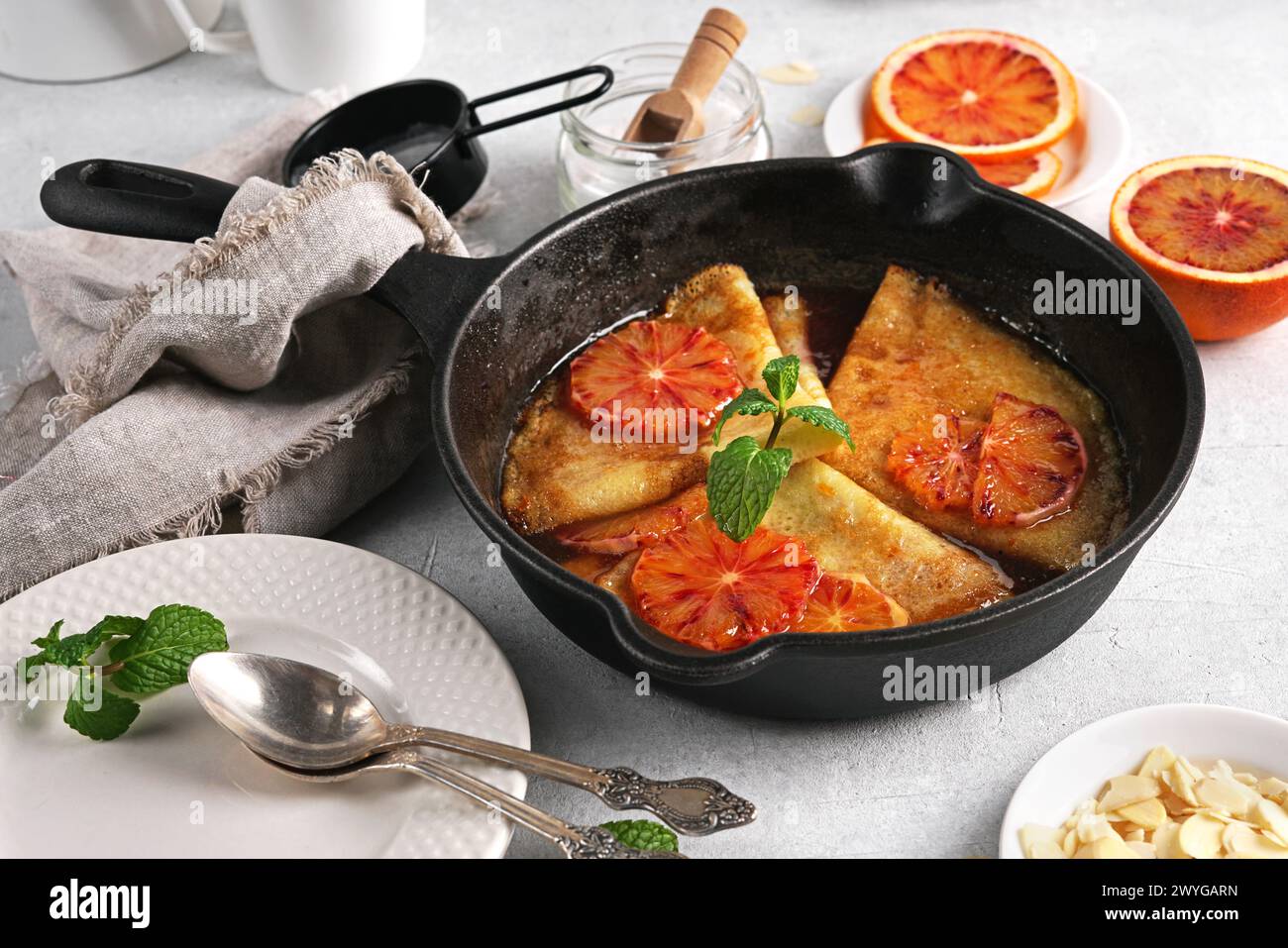 Crêpes à la sauce orange dans une casserole en fonte. Suzette traditionnelle en crêpe française avec sauce orange sur table lumineuse Banque D'Images