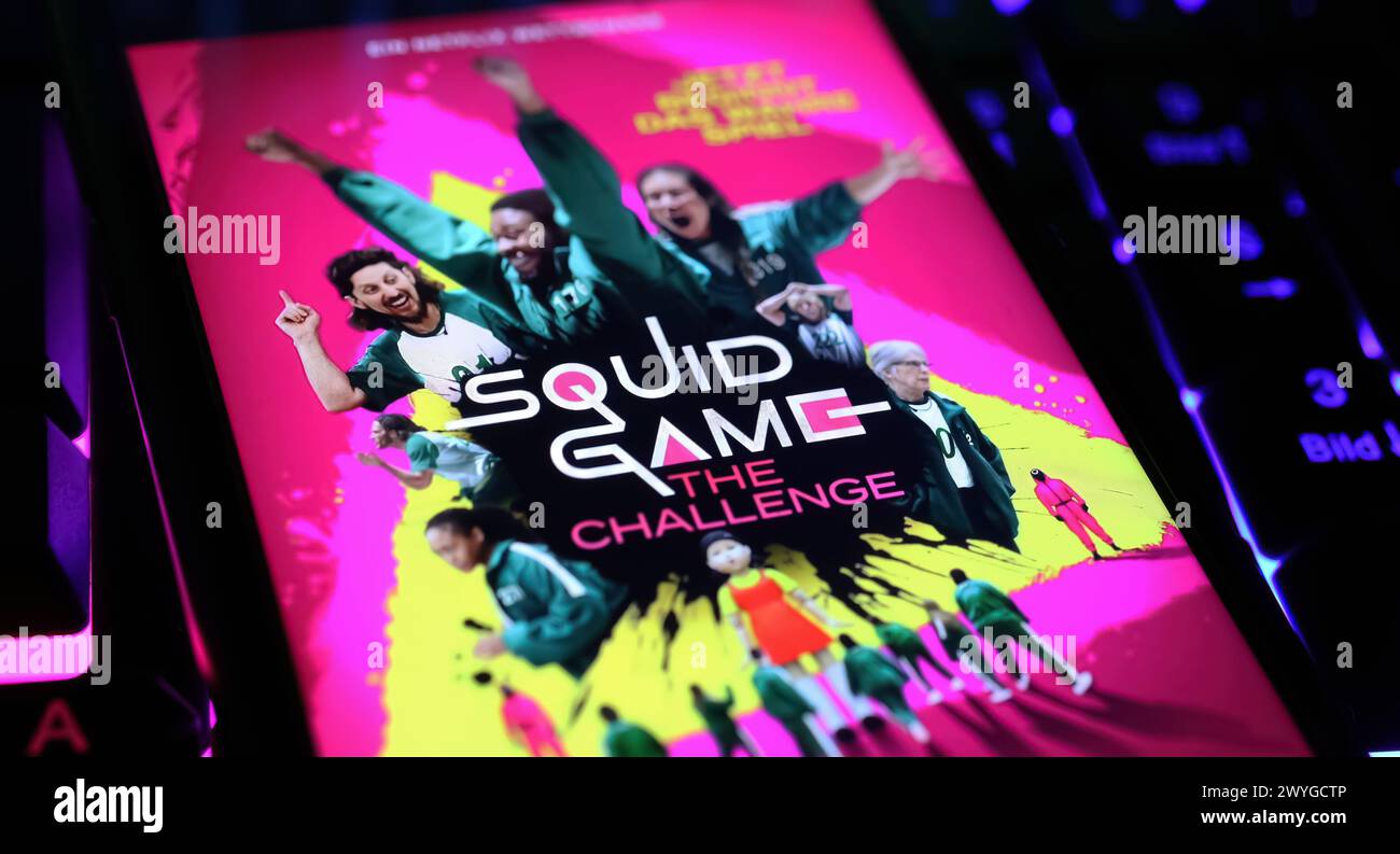 Viersen, Allemagne - 3 avril. 2024 : Netflix série Squid Game le défi affiche de couverture sur l'écran du smartphone sur le clavier de l'ordinateur Banque D'Images