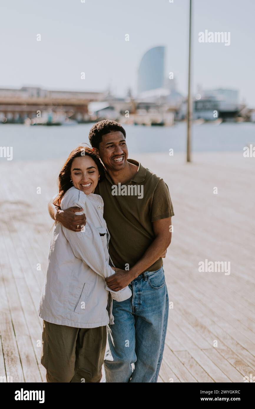 Joyeux couple embrasse sur un quai à Barcelone, avec l'horizon de la ville légèrement flou en arrière-plan Banque D'Images