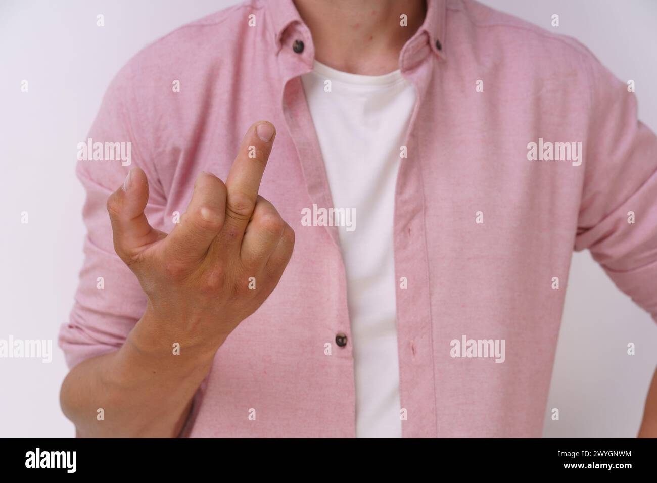 Un homme dans une chemise rose fait un geste de la main avec son pouce levé. Concept de frustration ou de gêne Banque D'Images