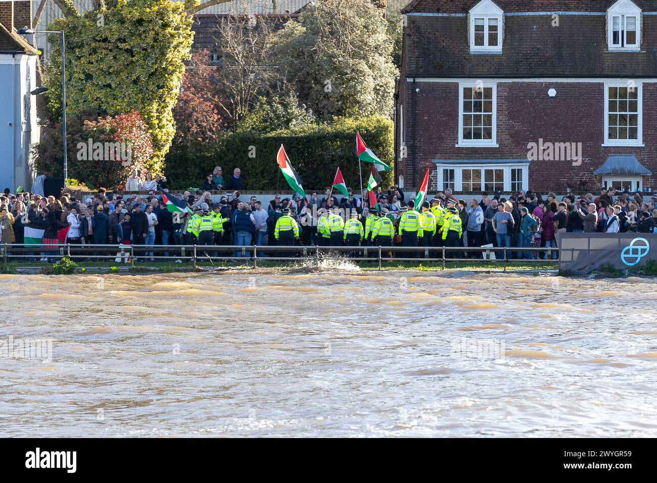 Samedi 30 mars 2024 Chiswick Bridge, Londres, Royaume-Uni. Les manifestants se sont rassemblés parmi les spectateurs qui regardaient la course de bateaux Gemini lors de la dernière course pour hommes. Les manifestants ont hissé des drapeaux palestiniens lors de la course finale et ont appelé à une Palestine libre afin de souligner le génocide continuel du peuple palestinien par Israël. Alors que Cambridge franchit la ligne d'arrivée, les membres du groupe Youth Demand ont laissé tomber une bannière et le drapeau palestinien. La police est rapidement intervenue et a enlevé le drapeau et la bannière, mais deux jeunes hommes ont réussi à se coller sur le pont. Abdullah Bailey/Alamy Live News Banque D'Images