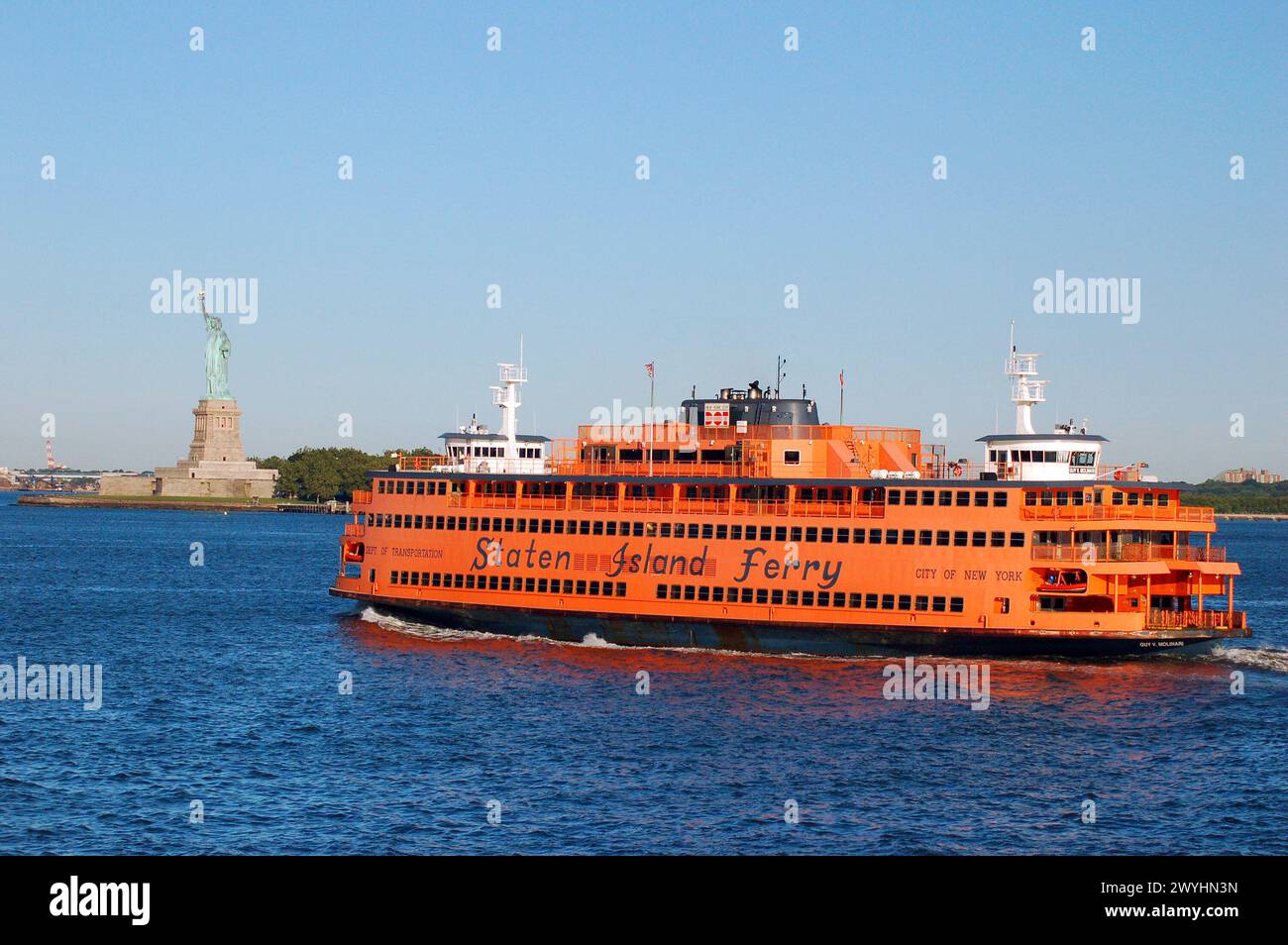 Le ferry orange Staten Island passe devant la Statue de la liberté pendant son trajet de Manhattan à Staten Island Banque D'Images