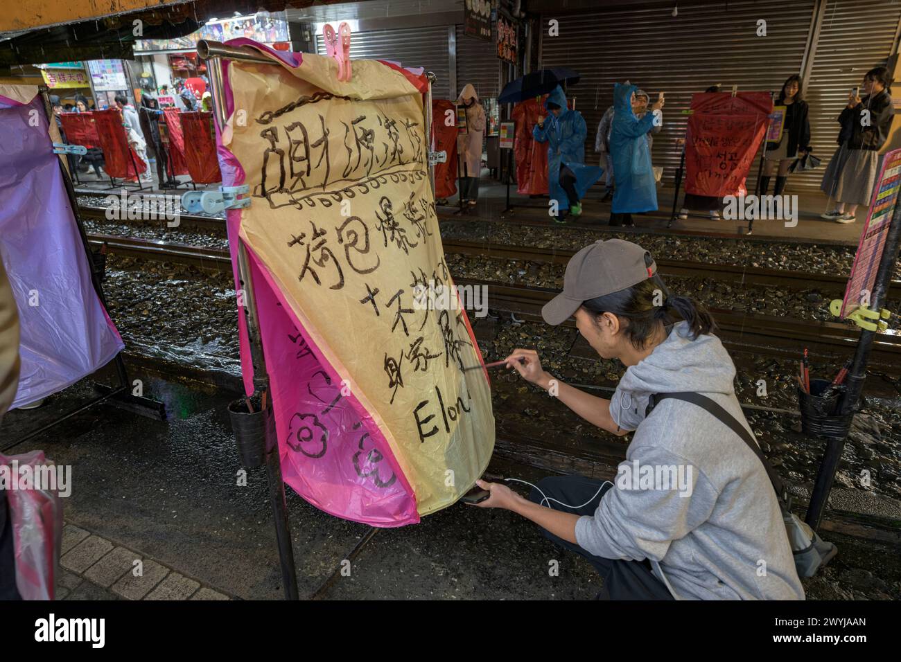 Jeune homme peint soigneusement la calligraphie sur une grande lanterne céleste pour faire un vœu pour le nouvel an chinois Banque D'Images