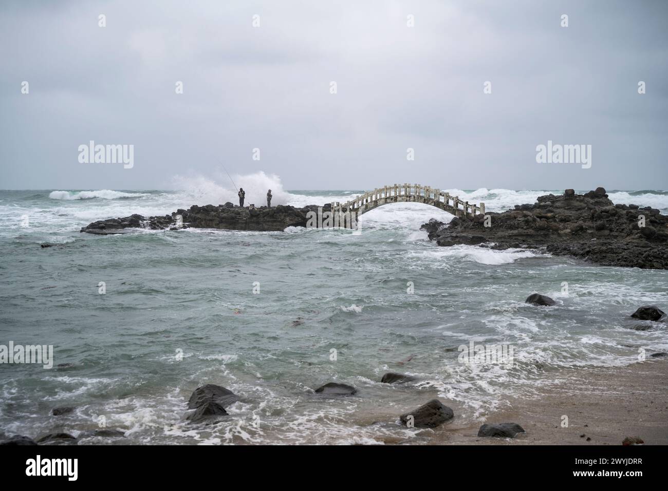 Pêcheurs pêchant à la ligne à partir d'un affleurement rocheux dans la mer par une journée nuageuse Banque D'Images