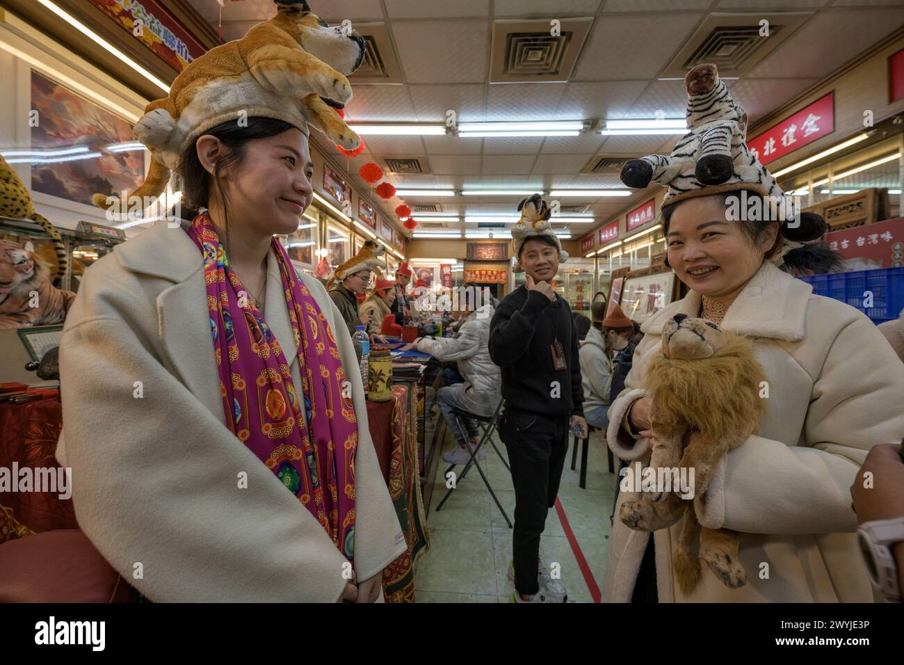 Un couple heureux pose avec des jouets tigres en peluche lors d'un événement festif dans une rue décorée pendant le nouvel an chinois. Banque D'Images
