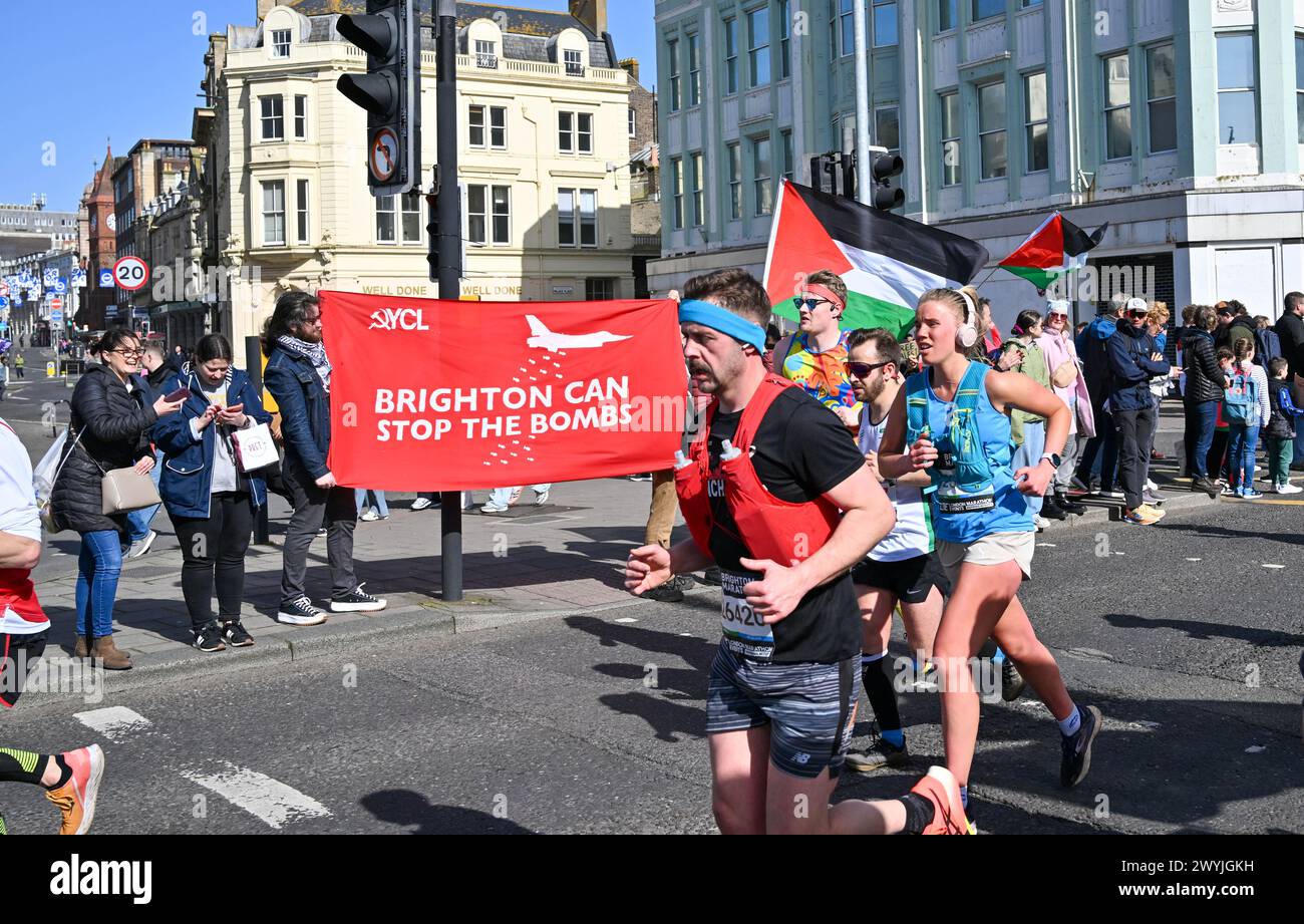 Brighton UK 7 avril 2024 - les manifestants Pro Palestine brandissent des drapeaux alors que des milliers de coureurs participent au marathon de Brighton par une journée ensoleillée mais venteuse : Credit Simon Dack / Alamy Live News Banque D'Images