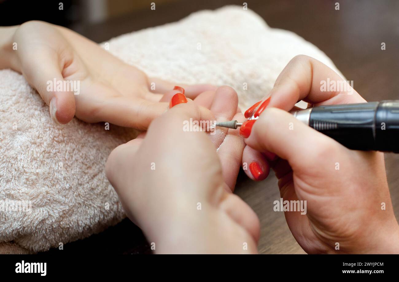 L'artiste ongle scie et attache une forme d'ongle pendant la procédure d'extensions d'ongles avec gel dans le salon de beauté. Soins professionnels pour les mains. Banque D'Images