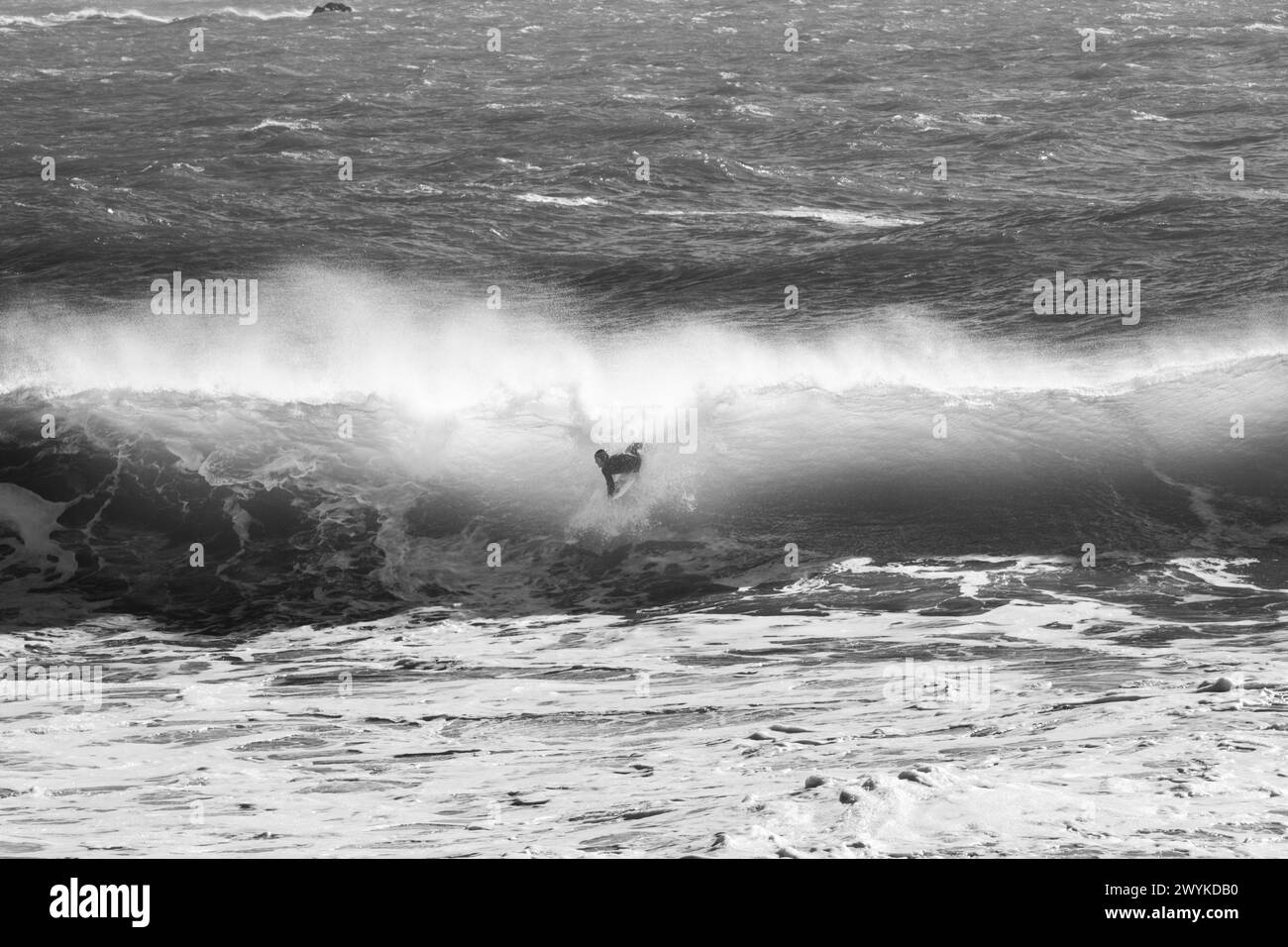 Planche à vagues ou planche de bodyboard dans les énormes Breakers à Kynance Cove, Cornwall. Braver les vagues. Image monochrome Banque D'Images