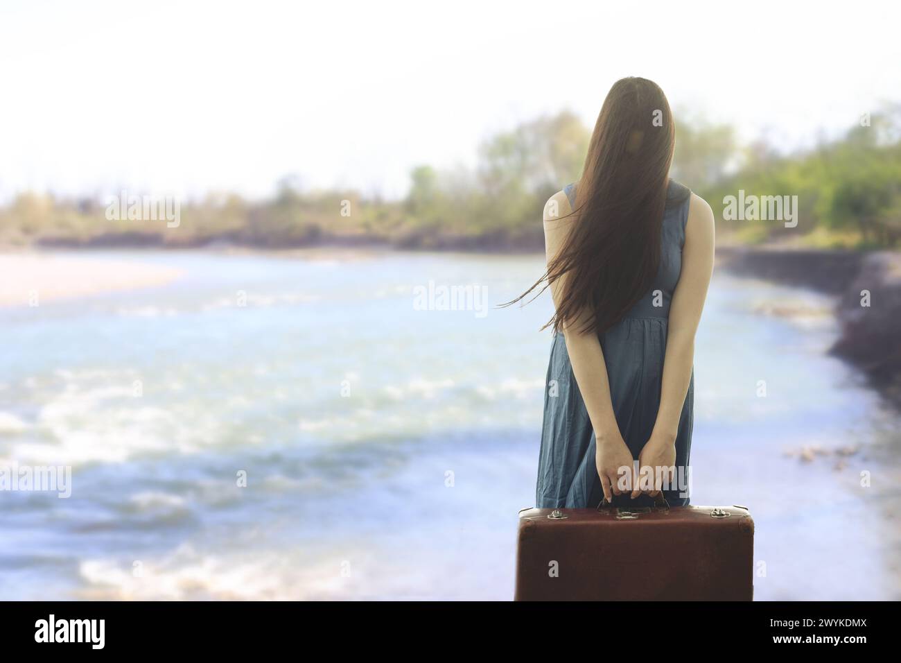 Femme surréaliste avec la valise et le visage couvert par ses cheveux commence son voyage vers l'avenir Banque D'Images