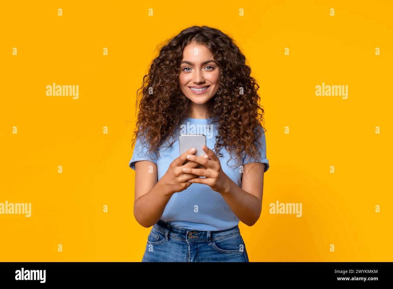 Femme de contenu utilisant un smartphone sur jaune Banque D'Images