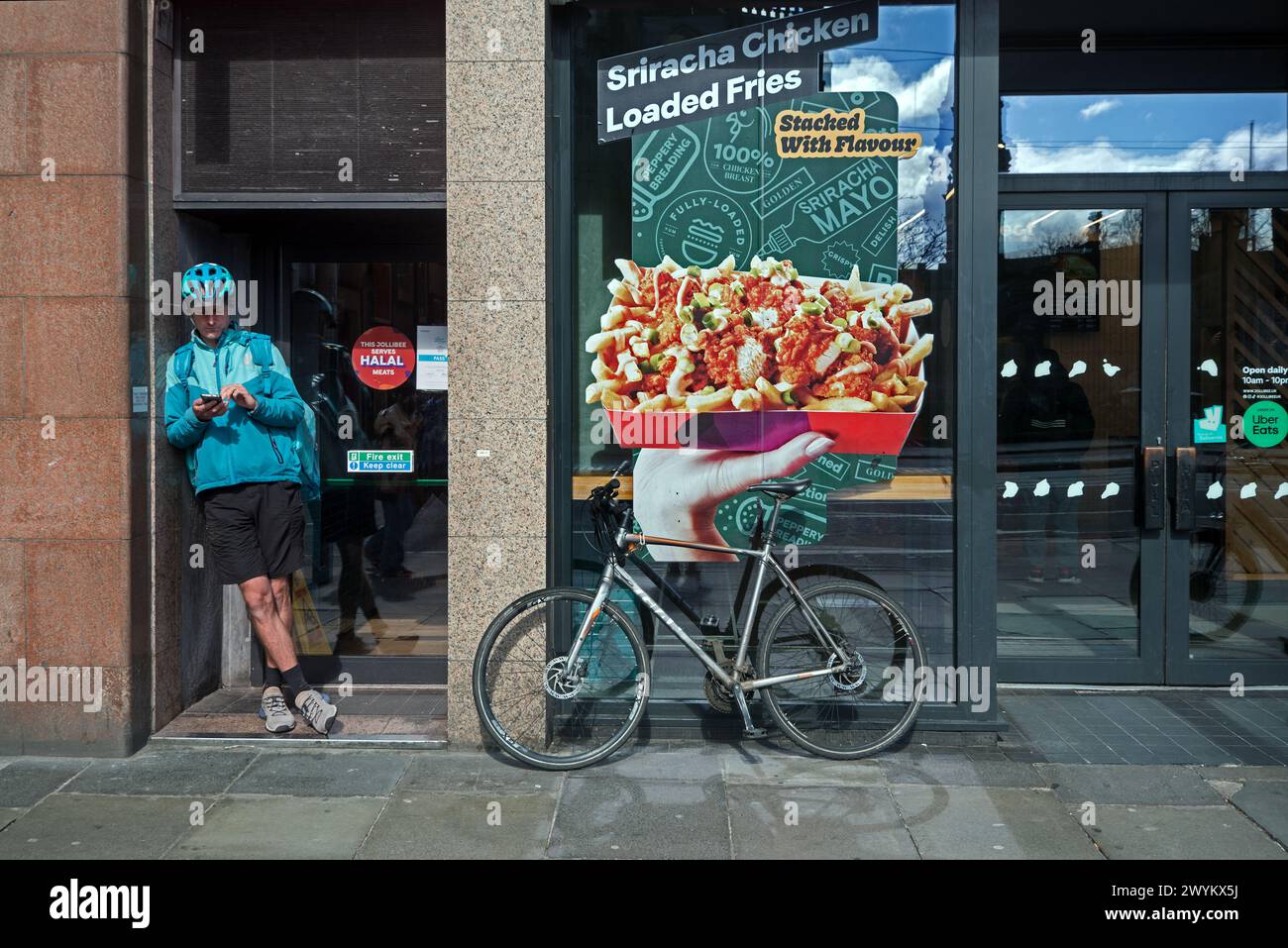 Livreur cycliste de livraison de nourriture vérifiant son téléphone sur Princes Street, Édimbourg, Écosse, Royaume-Uni. Banque D'Images