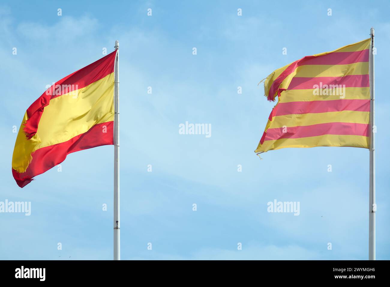 L'image capture un moment de coexistence pacifique, avec les drapeaux de Catalogne et d'Espagne agitant ensemble sous un ciel bleu clair, reflétant la culture Banque D'Images