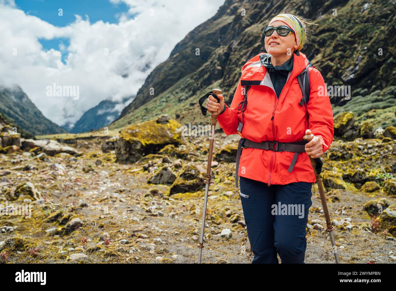 Portrait de femme dans des lunettes de soleil avec sac à dos et bâtons de trekking habillés veste softshell rouge randonnée sur Makalu Barun National Park trek au Népal. Moun Banque D'Images