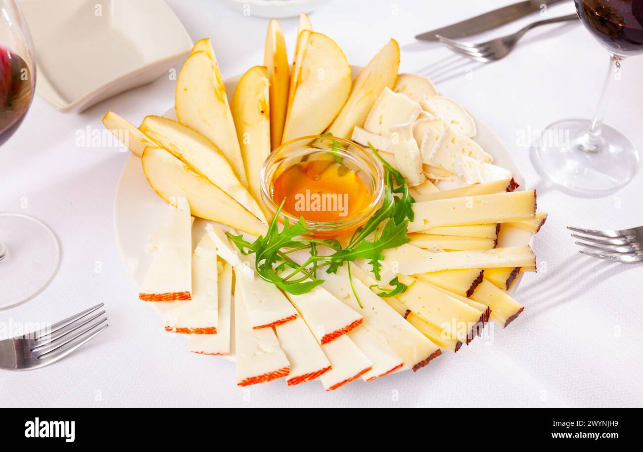 Assiette avec différents types de fromage et une tasse de miel Banque D'Images